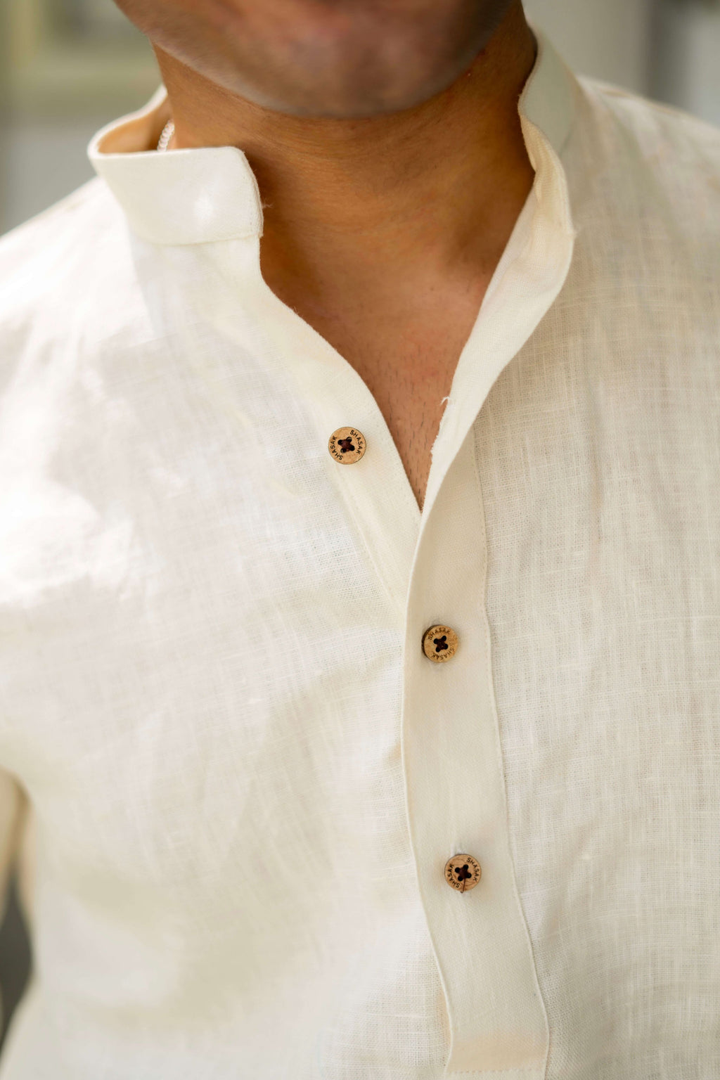 close-up view of off-white linen short kurta. featuring wooden buttons. 