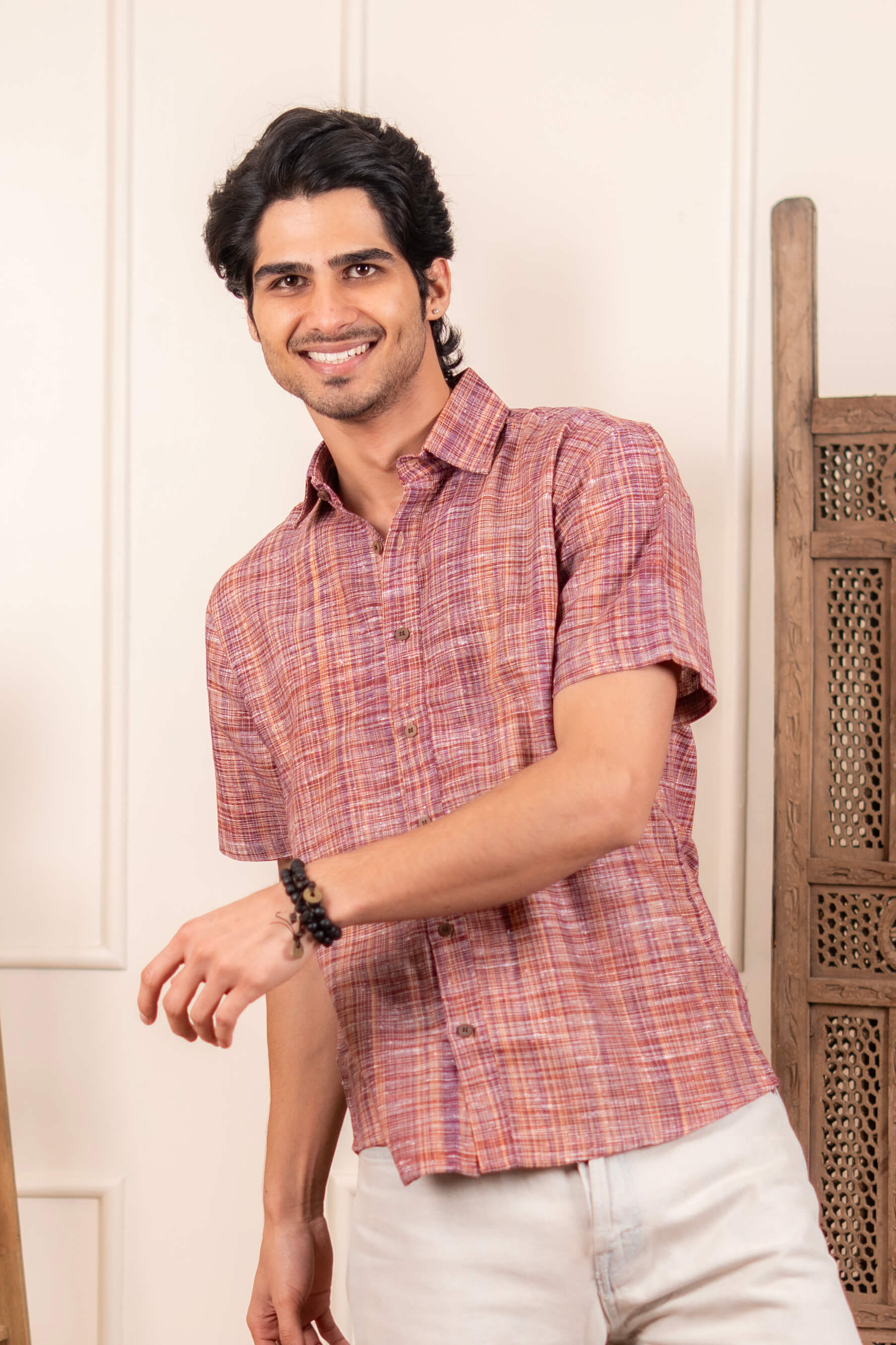 Man wearing a red and white checkered shirt against a white wall.