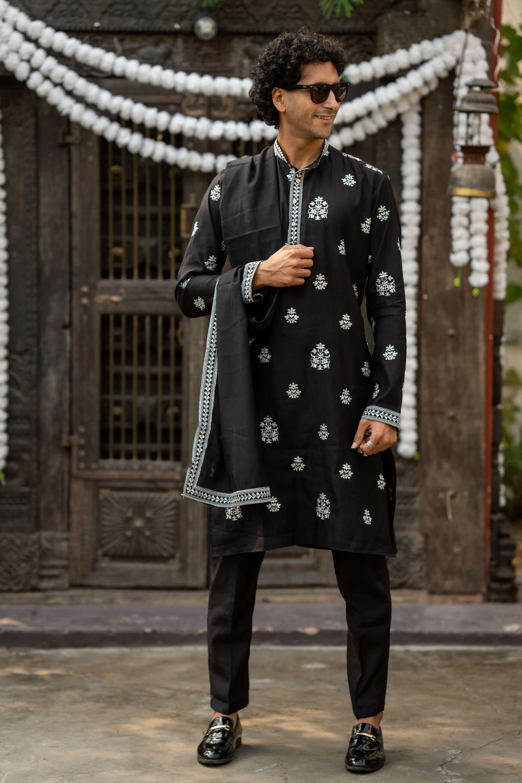 Man wearing a black embroidered kurta for men with dupatta, styled with black pants and formal loafers, perfect for weddings and festive occasions.