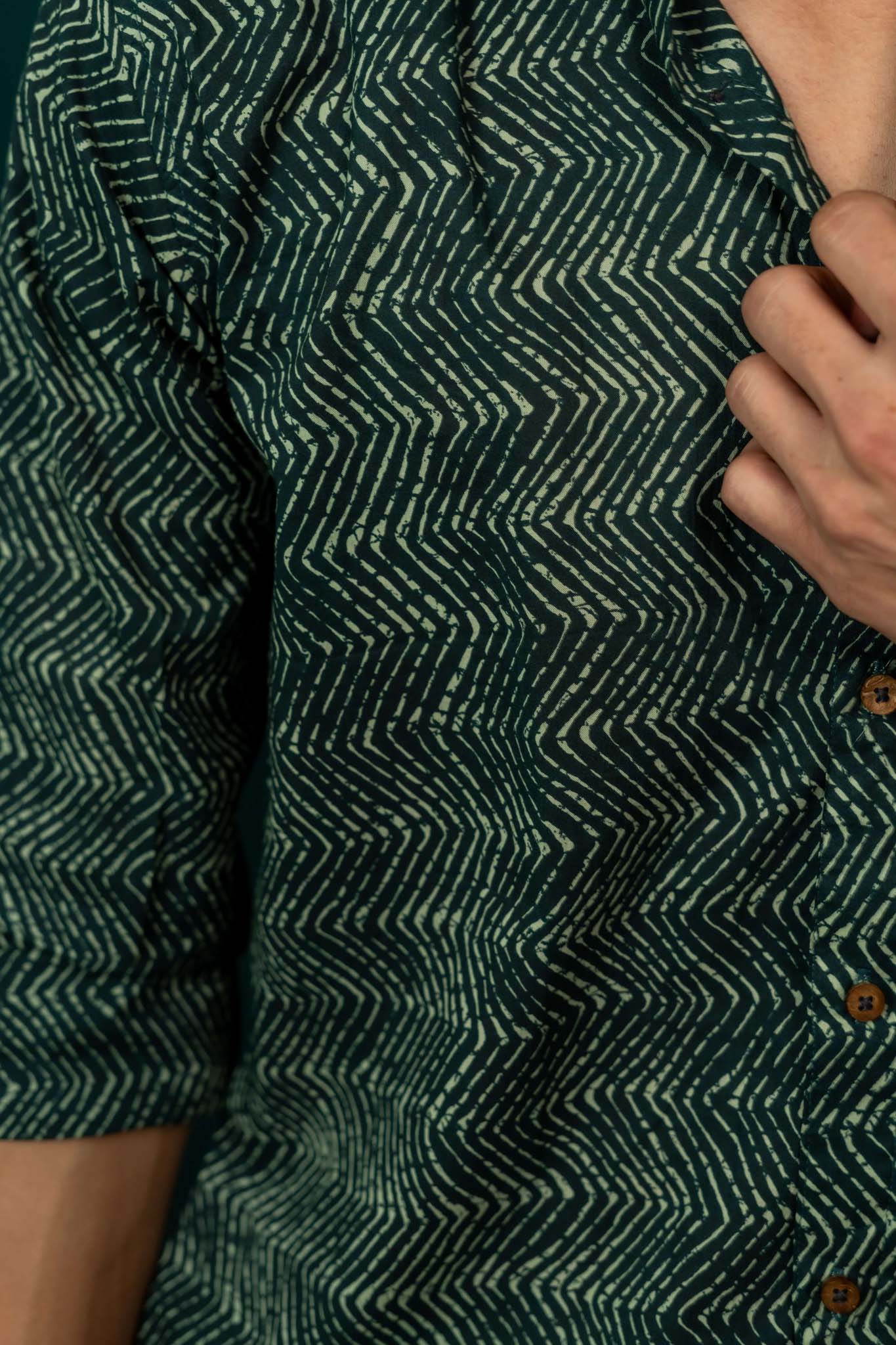 Close-up of a green patterned shirt with a hand adjusting it.